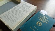 Two books on a wooden table; one is hardcover with a green cover, the other is in a box.