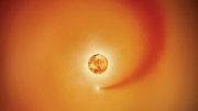 A glowing orange sun with a star and a trailing gas cloud in space.