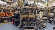 A complex laboratory setup with equipment, wires, and machinery in a spacious, well-lit room.