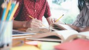 Young students writing with pencils on notebooks