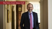 Alan M. Garber in a room in Massachusetts Hall with a red banner "The View from Mass Hall"