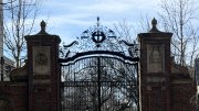 Brick entrance gates with a church in the background and snow on the ground.