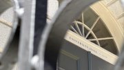 View of a building door labeled "University Hall" through a circular black railing frame.
