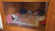 Cozy nook with a patterned rug and various colorful pillows against wooden walls.