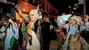 A lively street scene at night with people in colorful costumes dancing joyfully.