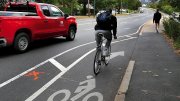 A cyclist rides in a bike lane that ends abruptly near a sidewalk as a red pickup truck passes nearby.