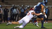 Columbia player is tackled from behind by a Harvard defender during a play.