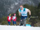 A man skiing intensely in the snow, with two spectators in the background.