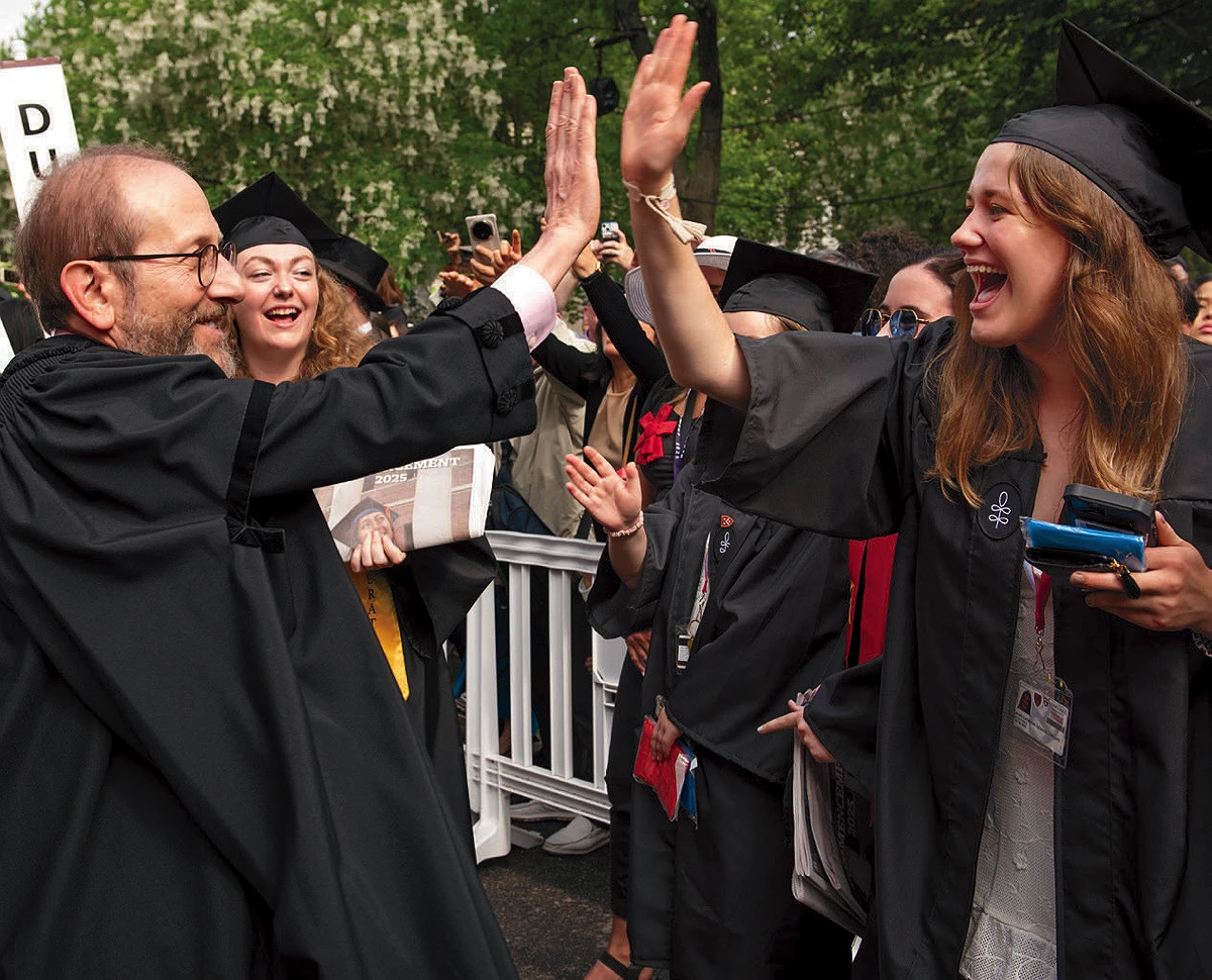 President Alan M. Garber high-fives a College senior during the morning procession