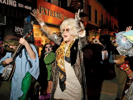 A lively street scene at night with people in colorful costumes dancing joyfully.