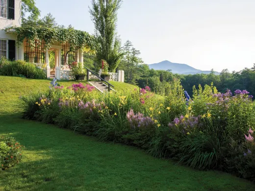 Garden view of Aspet, with vibrant flower beds and Mount Ascutney in the background.